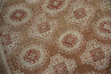 Detail of the worn, low-pile weave showing geometric guls in terracotta, copper, and ivory tones.