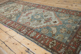 Distressed Malayer rug: terracotta geometric border, dusty teal primitive motifs, even wear.