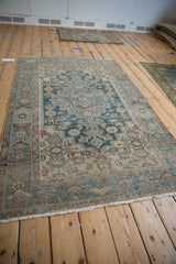 High-angle view of a vintage distressed Hamadan rug's soft blue, beige, and brown geometric pattern.