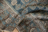 Worn texture and soft folds of a distressed Persian rug in dusty sapphire blue and beige.