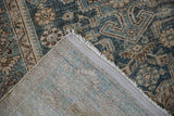 A folded corner of a vintage Hamadan rug reveals the hand-knotted pile and woven foundation.