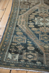 Distressed vintage Malayer rug, showing worn geometric patterns in dusty teal and beige.