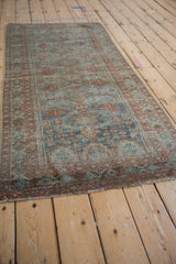 Distressed vintage Belouch rug runner end, displaying worn sapphire blue and terracotta gul motifs with fringe.