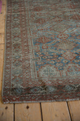 Distressed vintage Belouch rug corner, showing worn pile, geometric madder red, and sapphire blue border.