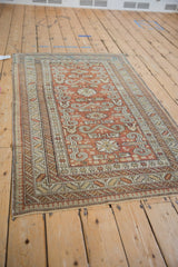 Angled perspective of an antique Shirvan rug with geometric Caucasian patterns in chestnut and ivory.