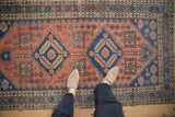 Vintage Heriz rug runner's sapphire blue medallion and coral geometric field, seen underfoot.
