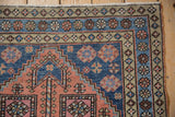 Heriz rug corner with blue and dusty blush geometric blossoms, showing secure selvage.