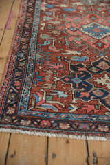 Curvilinear sapphire blue blossoms on the Heriz rug's cherry red field and geometric border.