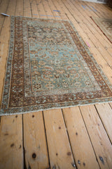Angled view of a distressed Malayer rug highlighting the textured powder blue field and chestnut border.
