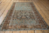 The allover Herati pattern and distressed texture of a vintage Persian Malayer rug viewed from an angle.