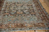Angled view of a distressed Malayer rug's textured low pile and exposed foundation.