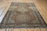 Vintage Karaja rug with textured wear, featuring faded floral pinwheel motifs and a starburst border.