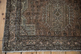 Distressed Karaja rug corner, showing starburst and floral borders with visible foundation and soft patina.