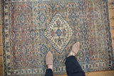 Overhead view of a vintage distressed Khorassan rug, showing its scale and intricate Herati pattern on the floor.