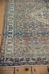 Angled view of the Khorassan rug's low pile and meandering floral border in beige and blue.