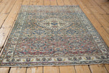 Angled view of the vintage Khorassan rug's distressed Herati design and central medallion.