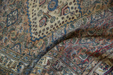 Folds in the distressed vintage Khorassan rug reveal its low pile and detailed floral motifs.