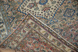 Folded corner of a distressed Khorassan rug highlighting the worn texture and detailed floral border.
