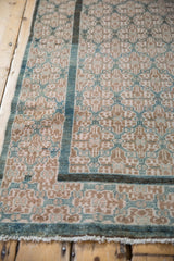 Vintage Malayer rug close-up: distressed pile, geometric lattice, dusty teal border, and fringe.