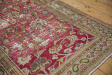 Distressed magenta field with sprawling vine motifs meeting pale blue paisley border.