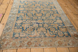 Distressed Malayer rug border: sky blue, terracotta floral and vine motifs, visible fringe.