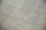 Distressed low pile on the corner of a vintage Khotan carpet in soft pink and blue hues.