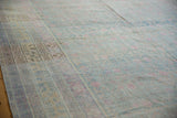 Low perspective across a distressed Khotan carpet showing the time-softened texture and faded pattern.