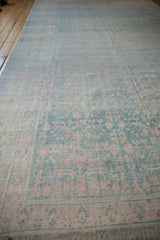 Long view of a vintage Khotan carpet with a distressed, allover pattern in soft blue, pink, and ivory.