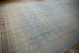 Soft, time-worn patina on a distressed vintage Khotan rug with faded blue and pink tones.