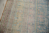 Soft, distressed texture with pink, blue, and saffron geometric patterns on a Khotan carpet.