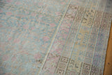 Distressed Khotan carpet showing faded blue and pink pomegranates alongside the saffron geometric border.