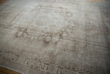 Angled view of a vintage Oushak carpet highlighting its distressed texture and faded medallion.