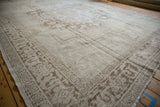 Distressed Oushak carpet's low pile texture and pale coffee brown stepped corner spandrel.