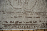 The distressed, low pile of a vintage Oushak carpet showing exposed foundation and coffee brown motifs.