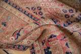 Distressed Joshegan carpet pile, folded, revealing wear, dusty pink, navy blue patterns.