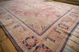 Distressed vintage Joshegan rug edge with reciprocating pawn border in dusty pink, navy, and sand.