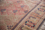 Decorative distressed Joshegan carpet showing worn pink field, intricate motifs, and navy border.