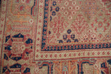 Distressed Joshegan carpet's navy reciprocating pawn border and worn red floral patterns.
