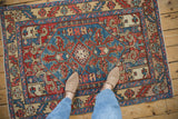 A person's view of a vintage Karaja rug showing the low pile and blue geometric medallion.