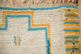 Vintage Moroccan rug detail showing thick geometric ivory, turquoise, and saffron yellow stripes.