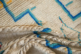 Folded detail of a hand knotted vintage Moroccan rug's thick ivory pile and blue pattern.