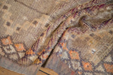 Textured pile detail of a distressed Moroccan rug, highlighting aubergine, saffron, and ivory tones.