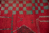 Close-up of the plush, hand-knotted wool pile showing the cherry red and turquoise checkered motif.