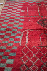 Detail of a Moroccan rug's even wool pile with red, turquoise, and ivory geometric motifs.