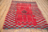 Angled perspective of a vintage Moroccan rug featuring its checkered pattern in red and turquoise.