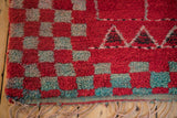 Braided fringe beside the plush, checkered wool pile of a vintage red and turquoise rug.