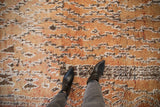 Shaggy wool pile of the distressed Moroccan carpet with faded gold, ivory, and brown tones.