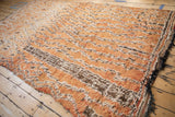 Shaggy, distressed pile of a Moroccan carpet in faded orange, brown, and ivory.
