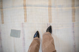 Detail of the distressed hemp kilim's textured flatweave with a silver patch and faded stripes.
