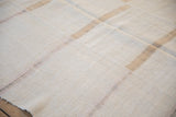 Close-up of the rustic, nubby texture of a hand-woven hemp kilim with faint, muted stripes.